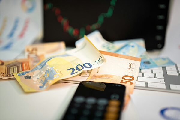 Banknotes on a desk beside a keyboard and a calculator