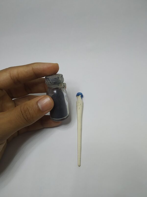 Hand holding a small bottle of black kohl powder beside a wooden applicator