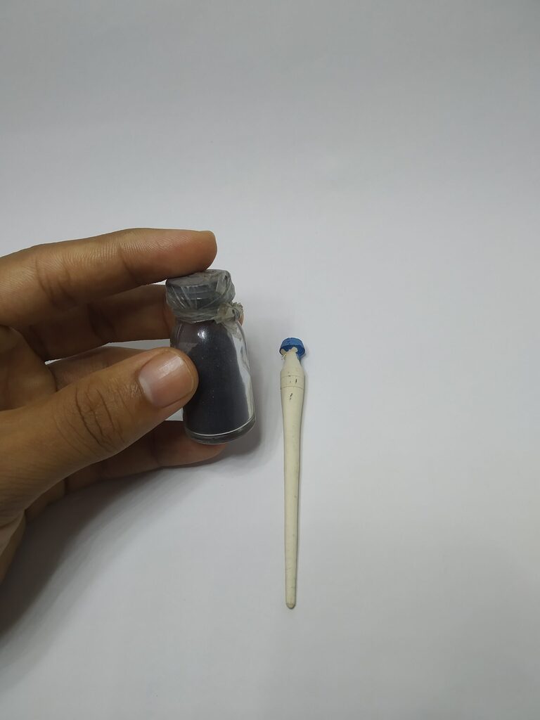 Hand holding a small bottle of black kohl powder beside a wooden applicator