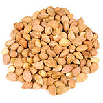 A mound of whole shelled mahaleb kernels with pale tan skins, a few split to show their cream interior, on a white background