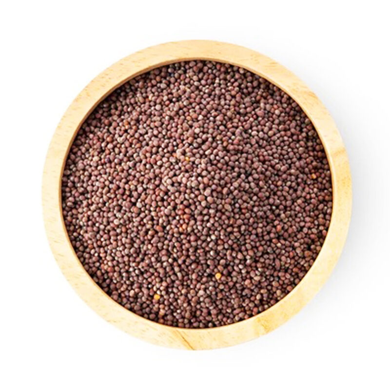 Top view of small round reddish-brown mustard seeds filling a light wooden bowl on a white background
