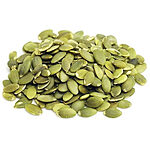 A heap of flat, oval green hulled pumpkin seeds in olive and pale green shades, on a white background