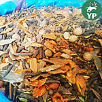 Whole spices heaped in a blue woven sack, with cinnamon bark, long pepper, nutmeg, mace, allspice berries and green cardamom pods