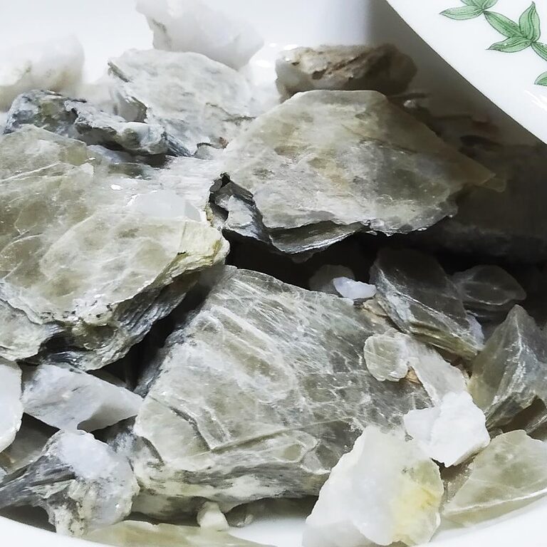 Pale translucent layered Hajar Nsar pieces piled in a white dish.