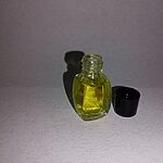 Hand holding a small clear glass bottle of yellow fragrance essence beside its black cap