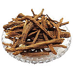 Long, wrinkled brown dried anacyclus roots, some with pale fibrous crowns, piled on a clear cut-glass dish