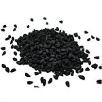 Loose matte-black black seeds scattered around a pile on a white background