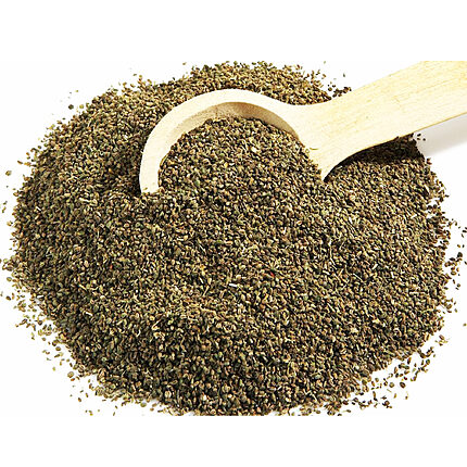 Whole green-brown celery seeds spread beside a wooden scoop on a white background