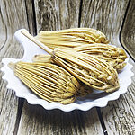 Several whole dried khella umbels with golden straw-like rays in a white scalloped dish on a weathered wooden surface