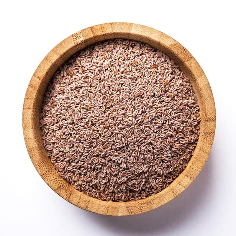 Whole pinkish-beige psyllium seeds heaped in a round bamboo bowl, seen from above on a white background