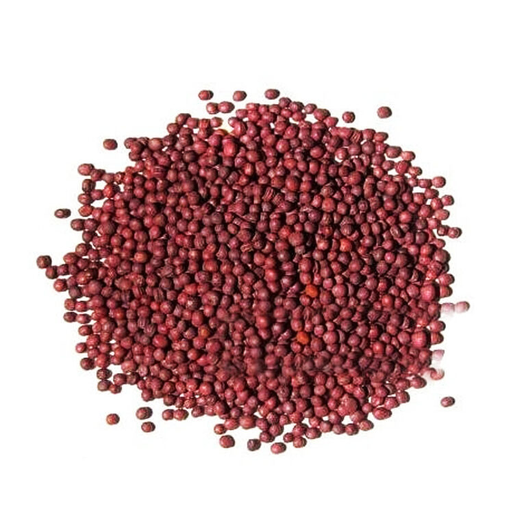 A round mound of tiny, smooth rose-red turnip seeds scattered on a white background