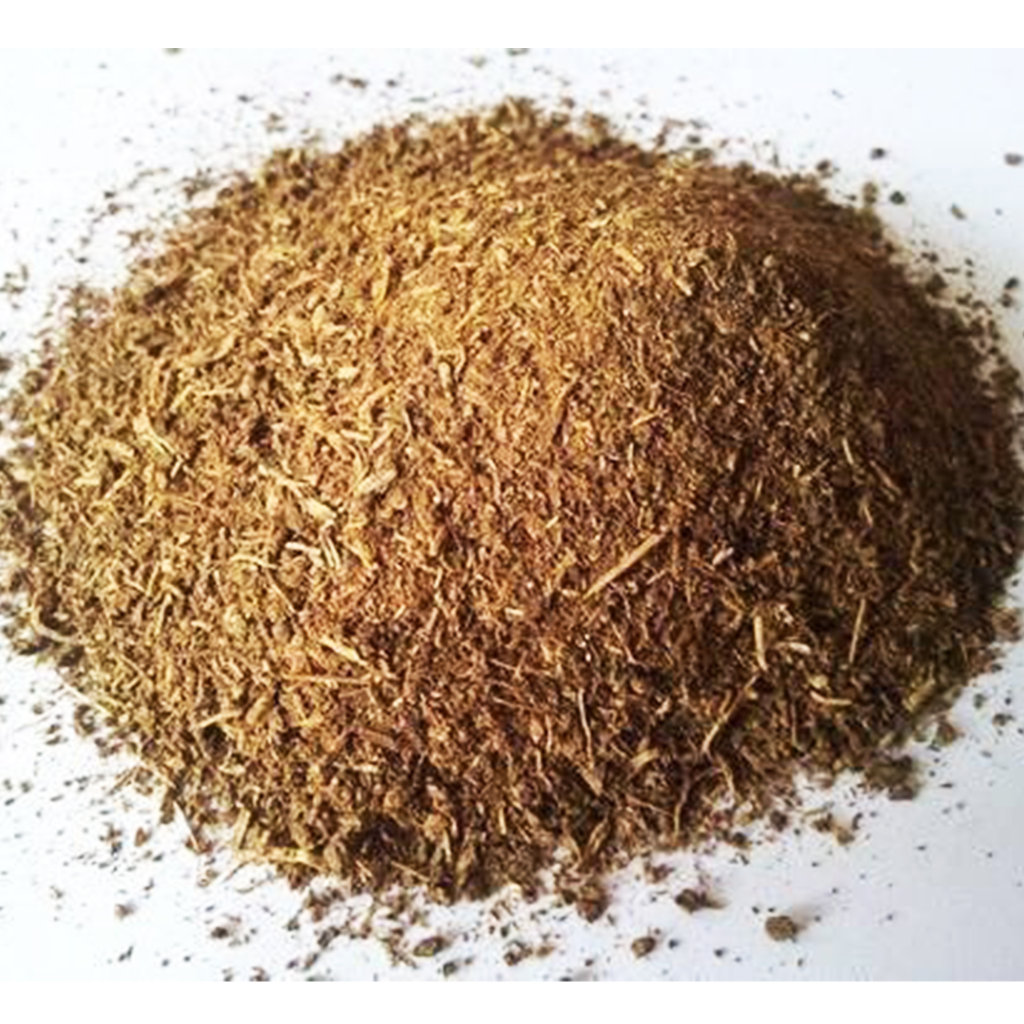 Indian costus root powder A loose mound of coarse tan-brown Indian costus root powder spread across a plain white surface.