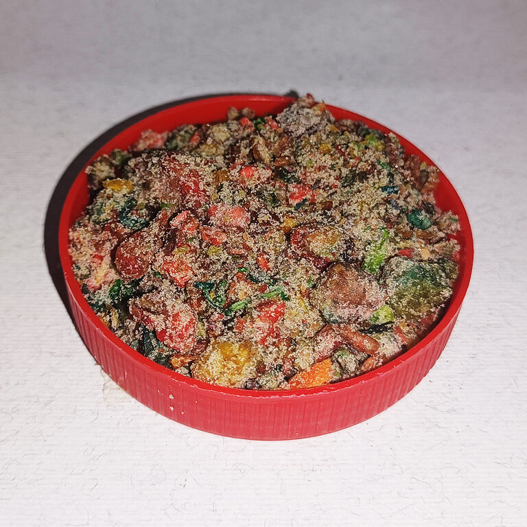 Round red lid filled with coarse multicolored incense pieces