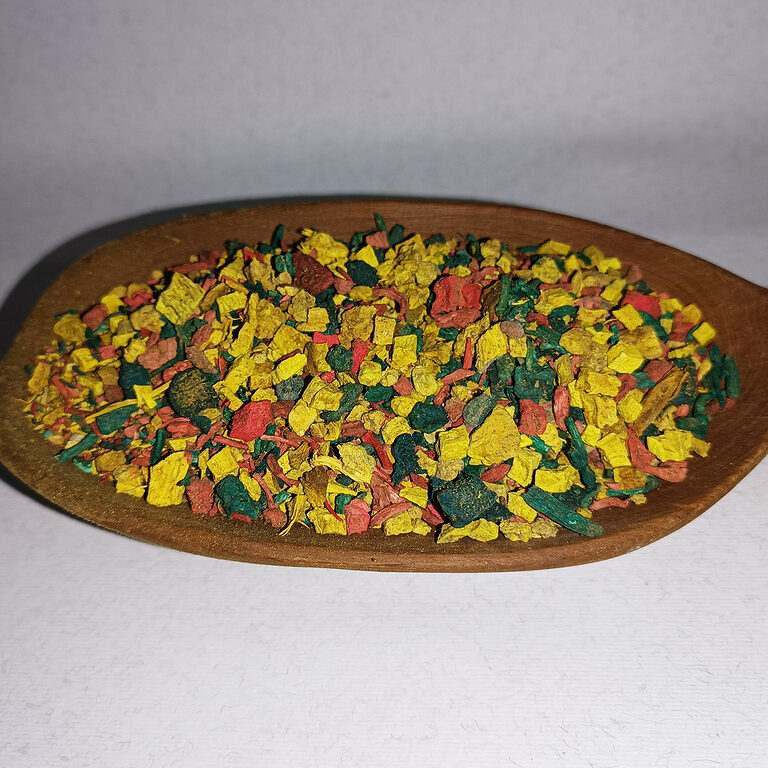 Colorful dry Sarghina bakhour pieces in a shallow wooden dish on a white background