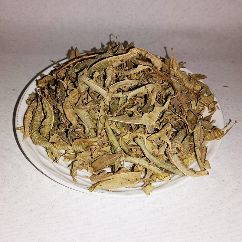Loose dried lemon verbena leaves and fine stems piled on a round white plate