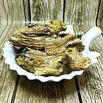 Whole dried calamus root pieces piled on a white leaf-shaped dish