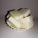 Pale ivory solid perfume blocks stacked on a small white scalloped dish.