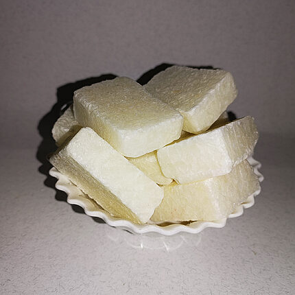 Pale ivory solid perfume blocks stacked on a small white scalloped dish.