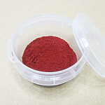 Deep red Aker Fassi powder in an open clear round container
