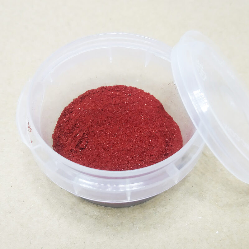 Deep red Aker Fassi powder in an open clear round container