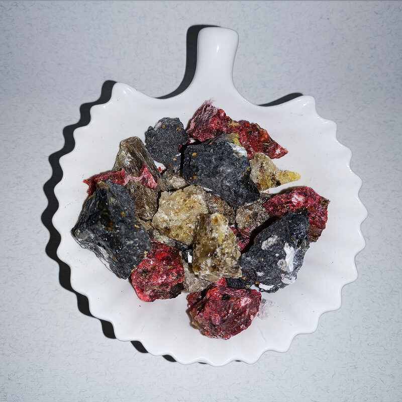 Assorted black, red, amber and brown resin chunks on a white scalloped dish