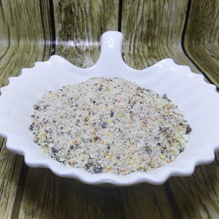 Coarse pale incense powder with yellow, amber and darker flecks in a white scalloped dish.