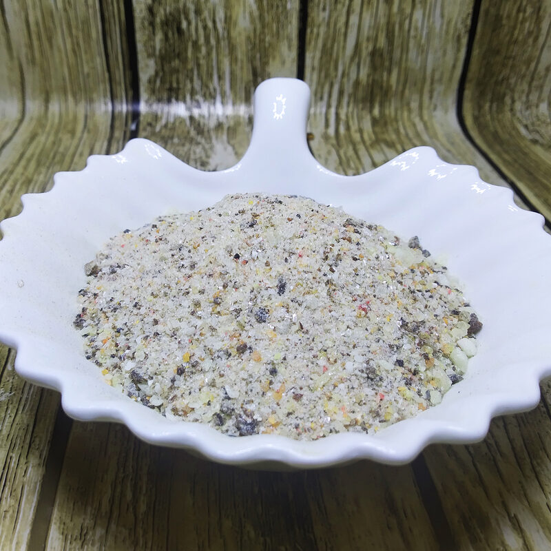 Coarse pale incense powder with yellow, amber and darker flecks in a white scalloped dish.