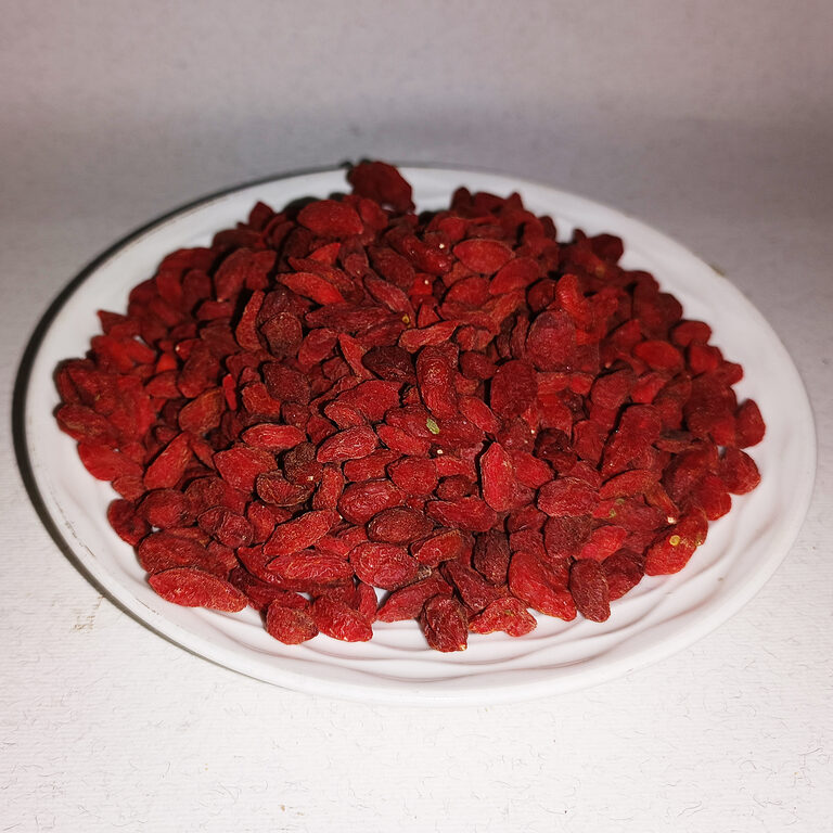 Deep red dried goji berries piled on a white plate