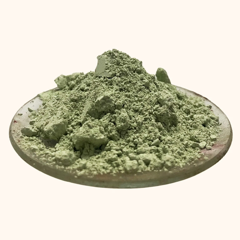 Pale green clay powder with natural clumps piled on a shallow dish