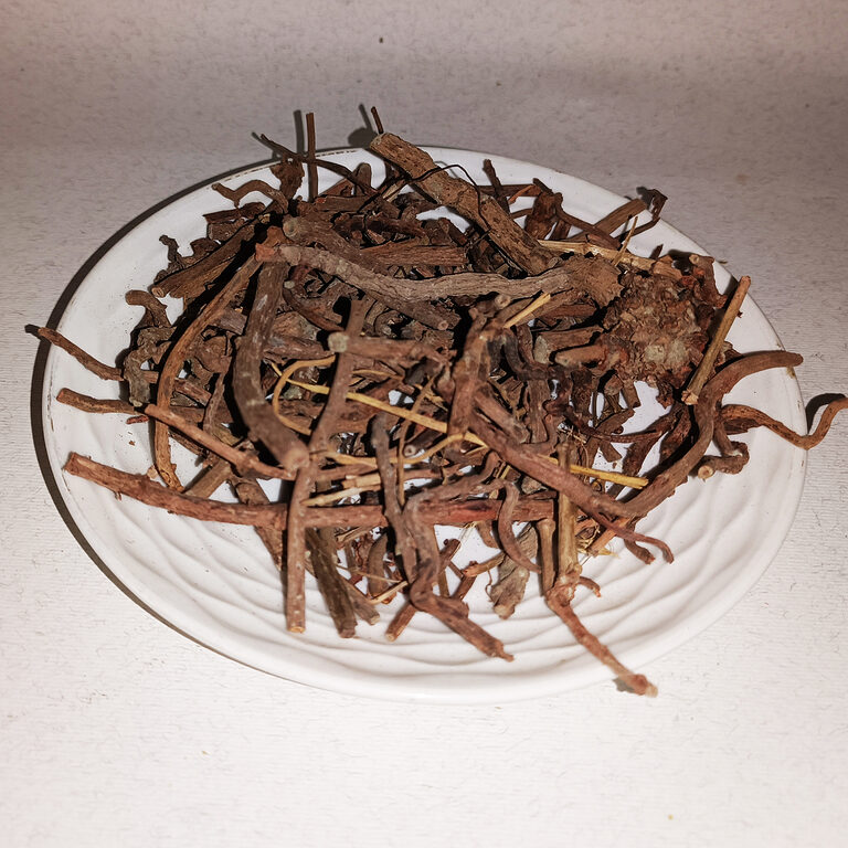 Loose reddish-brown dried madder root pieces on a white plate