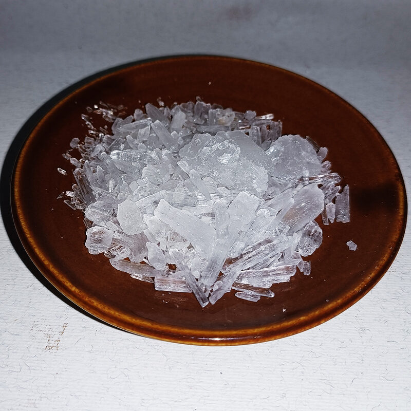 Cristaux de menthol translucides en vrac présentés dans une coupelle brune