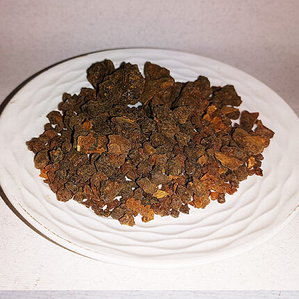 Morceaux de résine de myrrhe bruns et ambrés disposés sur une assiette blanche en céramique.