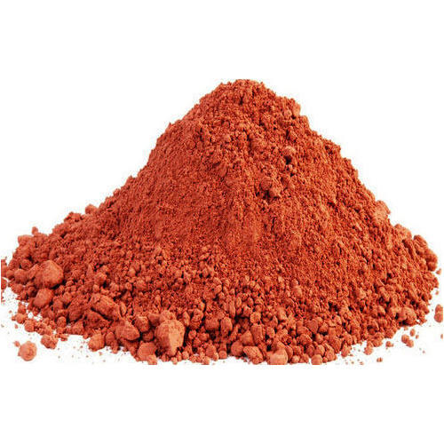 Loose mound of finely ground terracotta-red clay powder on a white background