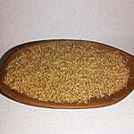 Chopped dried wormwood with fine pale stems piled on a round wooden plate