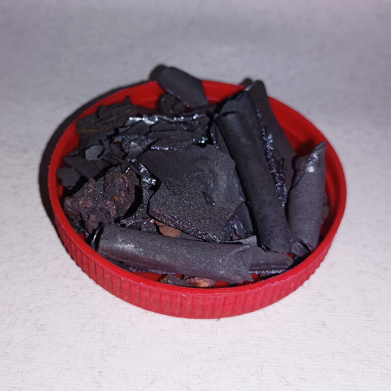 Dark brittle Hdida Hamra flakes arranged in a red lid