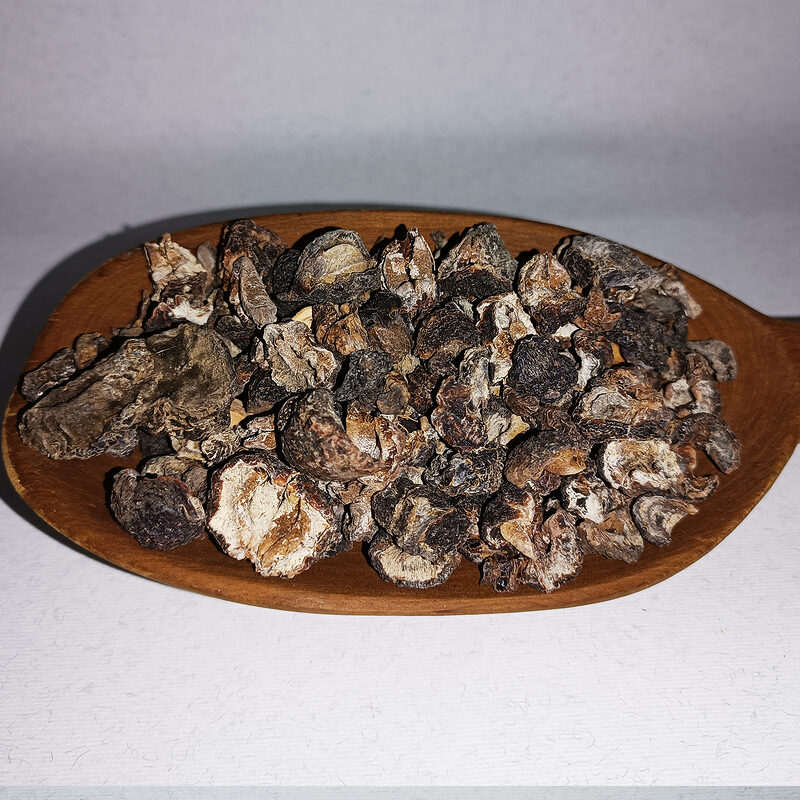 Dark dried amla fruit pieces piled on an oval wooden dish