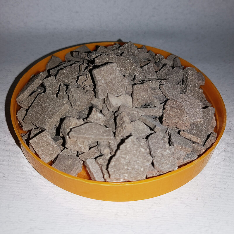 Grey-brown dry rhassoul clay pieces in a round orange dish.