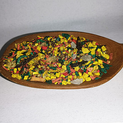 Colourful loose incense blend with yellow, green and pink pieces in a wooden bowl