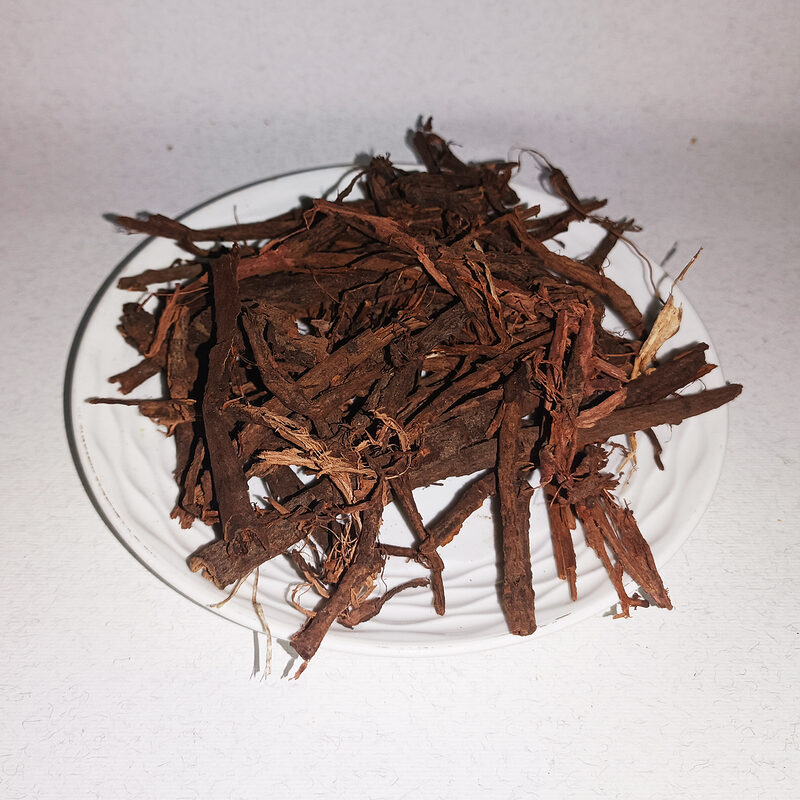 Loose reddish-brown dried dbagh root pieces piled on a white plate.