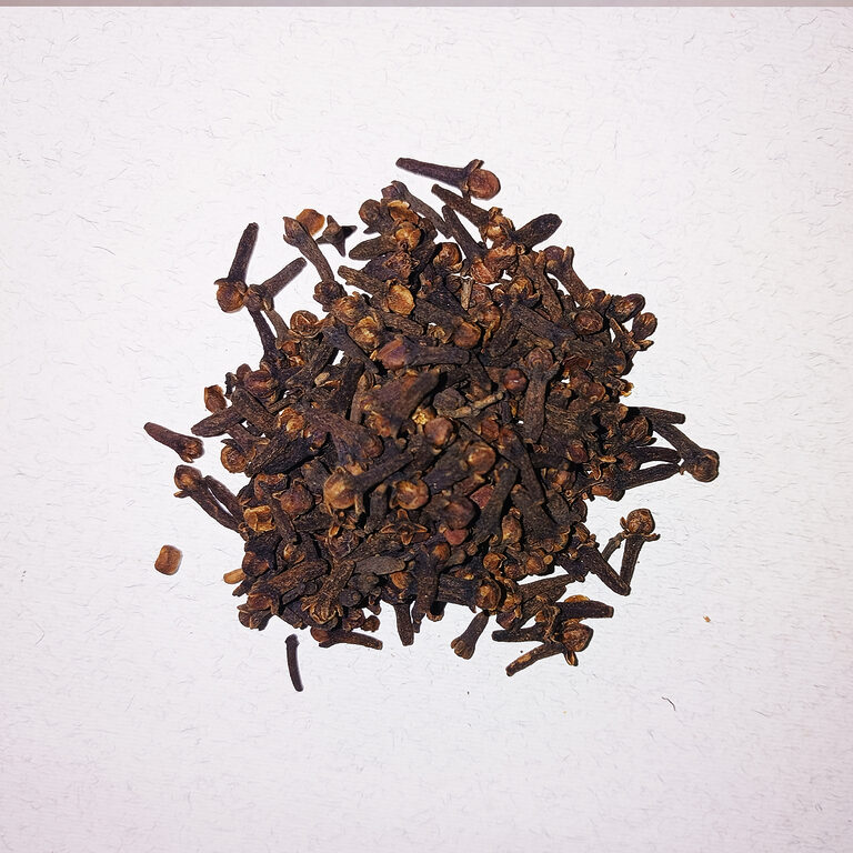 Pile of whole dried cloves on a white textured surface