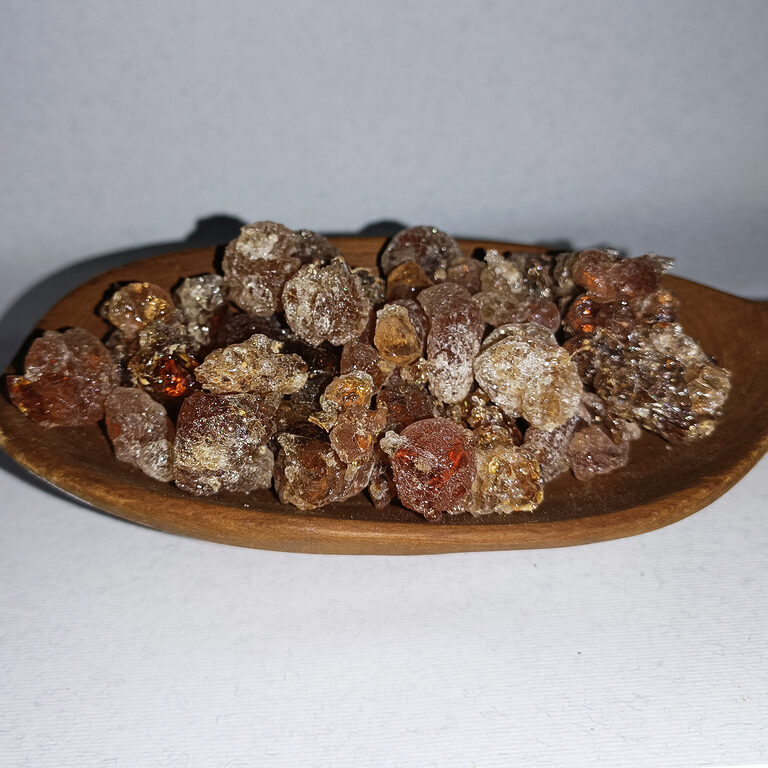 Clear, amber and reddish gum Arabic resin tears arranged on a round wooden plate.