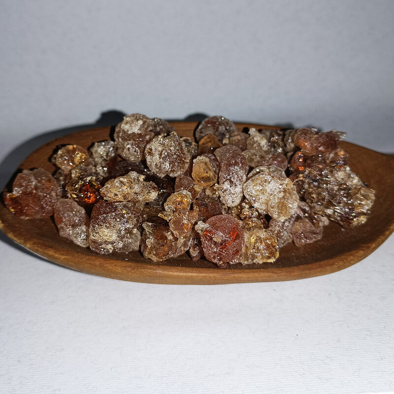 Clear, amber and reddish gum Arabic resin tears arranged on a round wooden plate.