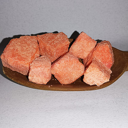 Rough peach-pink Yemeni alum stone pieces arranged on a wooden dish
