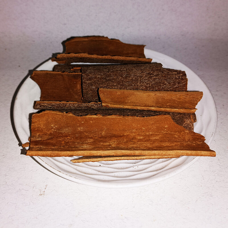 Brown cinnamon bark strips stacked on a white plate