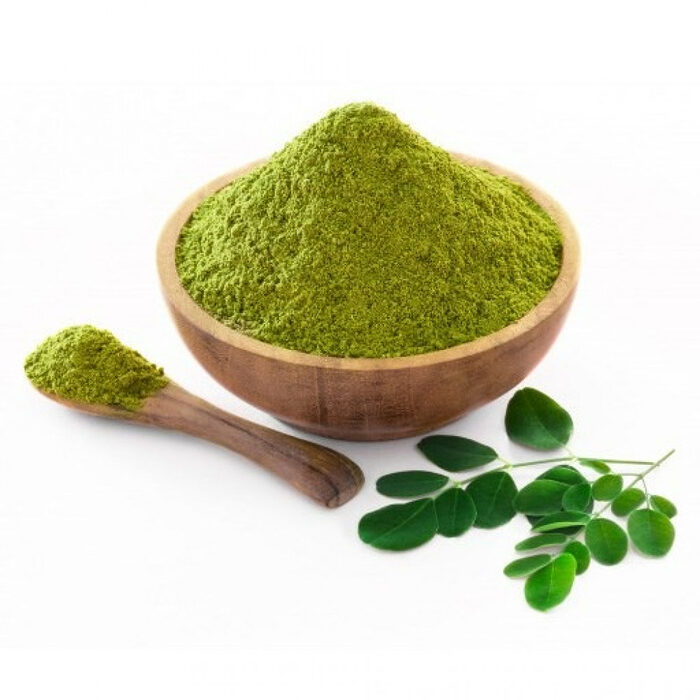 Fine green sidr leaf powder in a wooden bowl with a wooden spoon and fresh leaves