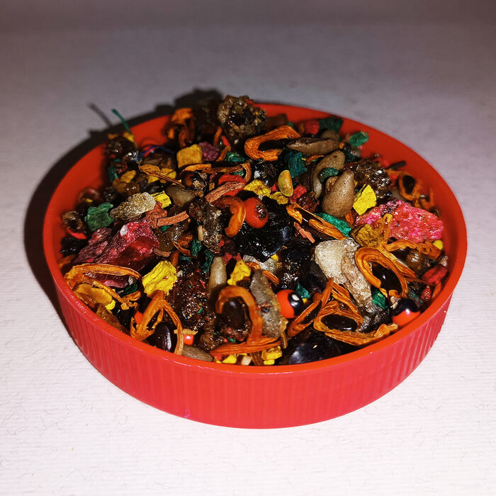 Colourful loose sweet Tfosikha bakhour with dark glossy pieces, dried botanical fragments and bright accents in a red dish.