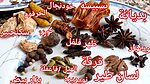 Whole spices laid out on a white floral plate with red Arabic labels, including ginger, turmeric, galangal, mace, star anise, nutmeg, long pepper, cardamom, cinnamon and cloves